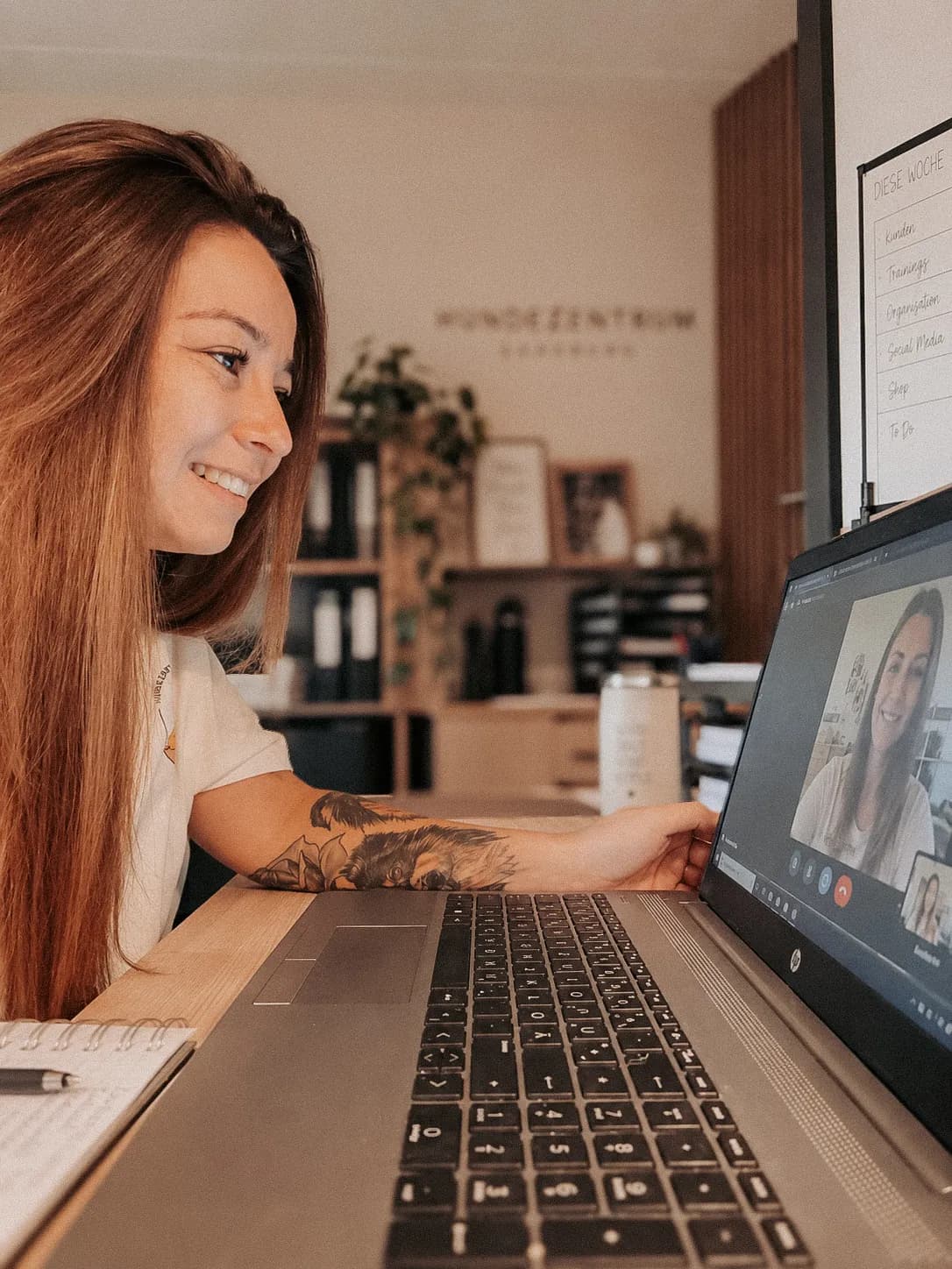 Trainerin im Profil vor dem Laptop, auf dem Bildschirm läuft die Videokonferenz
